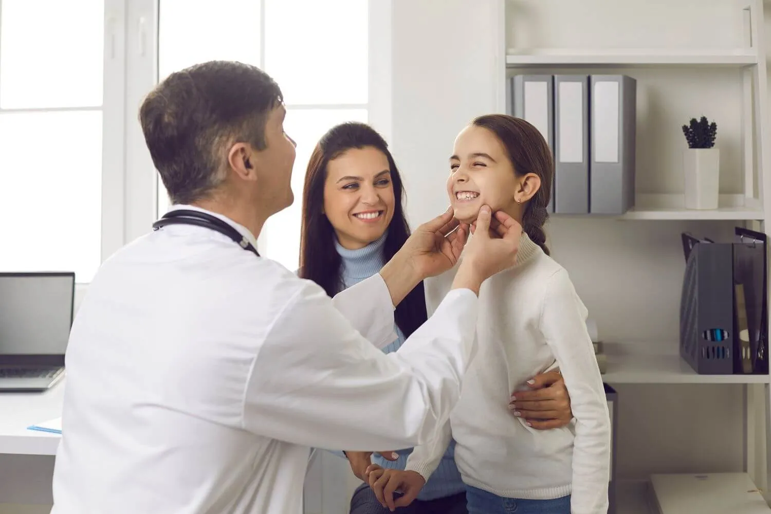 Child having her teeth examined with her mother beside her